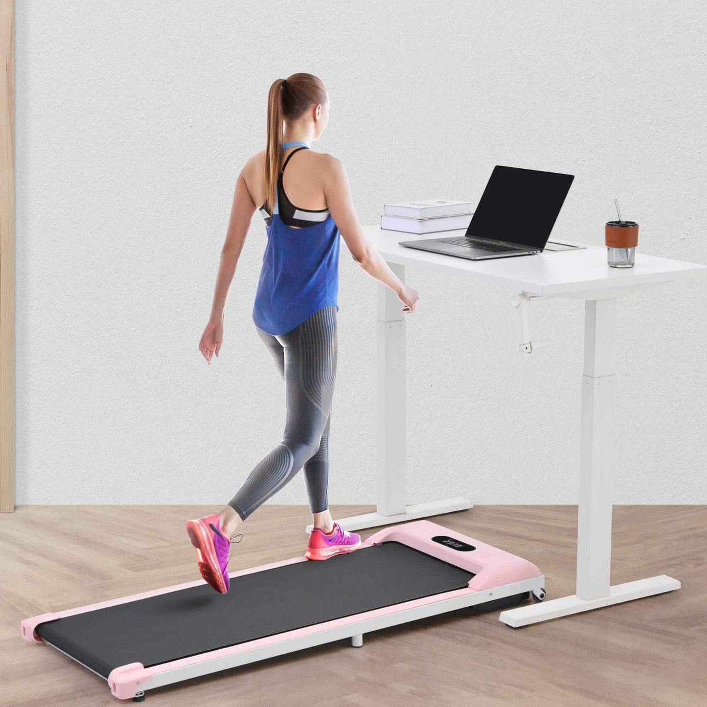 Class A under desk treadmill with Bluetooth in pink used by woman walking next to standing desk